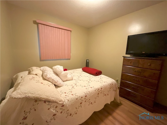 bedroom with light hardwood / wood-style floors and a textured ceiling