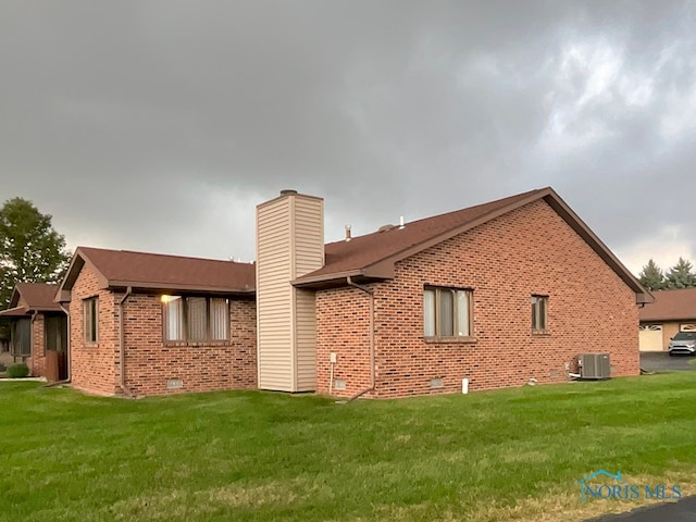 view of side of property featuring a lawn and cooling unit