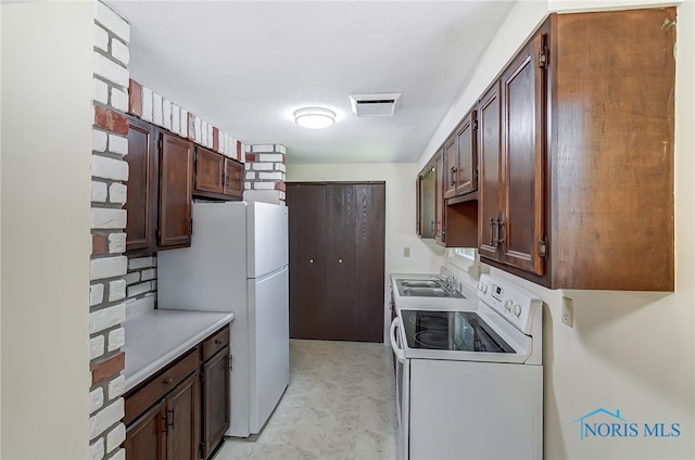 kitchen with dark brown cabinets, white appliances, and sink