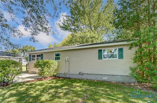 back of property with a lawn and a patio