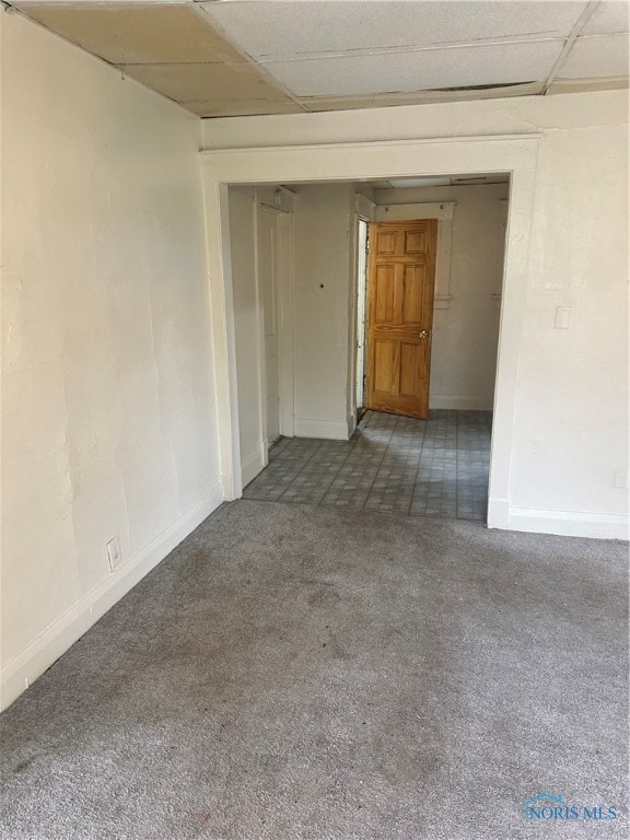 carpeted empty room featuring a drop ceiling