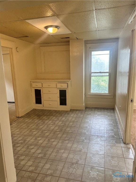 unfurnished living room featuring a drop ceiling