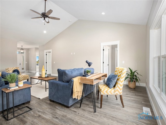 living room featuring hardwood / wood-style flooring, ceiling fan with notable chandelier, and high vaulted ceiling