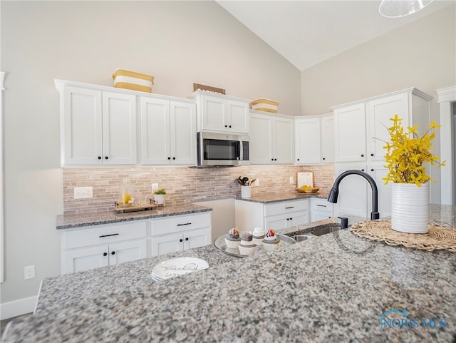 kitchen with white cabinetry, sink, and light stone countertops