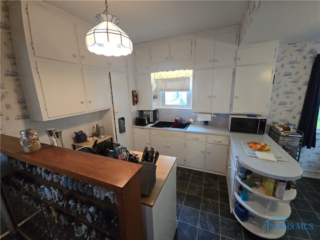 kitchen featuring white cabinetry, sink, dark tile patterned floors, and decorative light fixtures