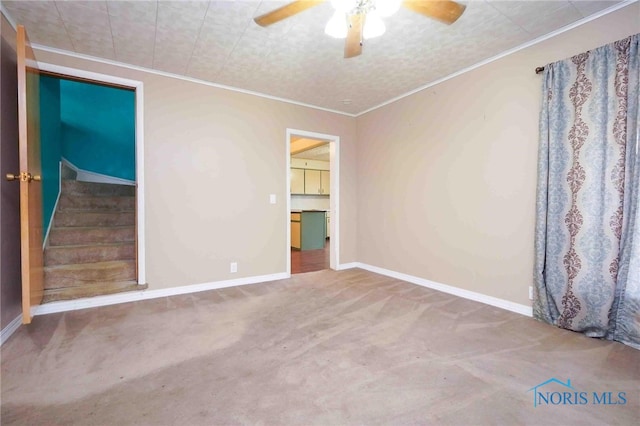 carpeted empty room featuring ceiling fan and crown molding