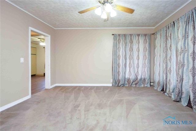 carpeted spare room featuring ceiling fan and crown molding