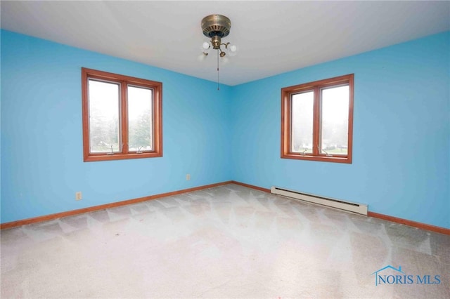 carpeted empty room featuring a baseboard radiator and a wealth of natural light