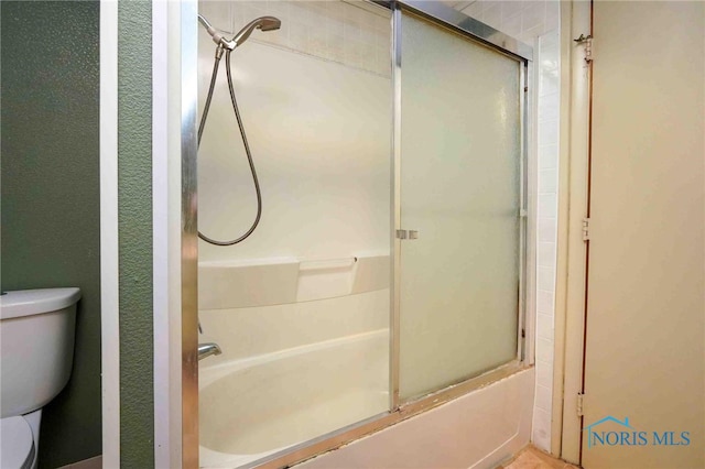 bathroom featuring shower / bath combination with glass door and toilet