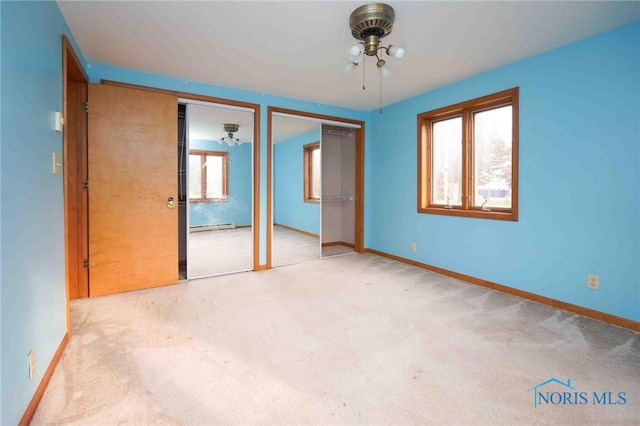 unfurnished bedroom with light colored carpet, two closets, and multiple windows