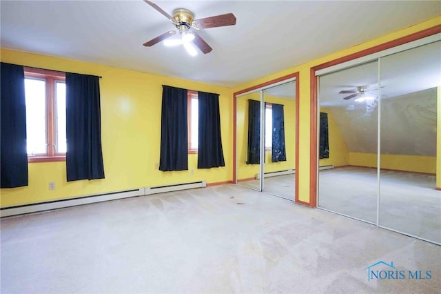 unfurnished bedroom featuring light carpet, multiple closets, ceiling fan, and baseboard heating