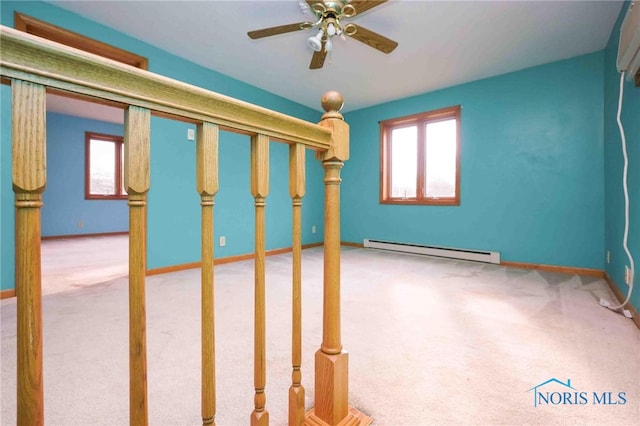 interior space with baseboard heating, light carpet, and ceiling fan