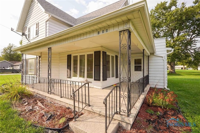 view of side of home featuring covered porch and a yard