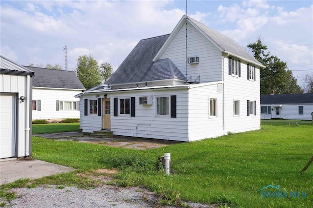 rear view of house featuring a lawn, an AC wall unit, and a garage