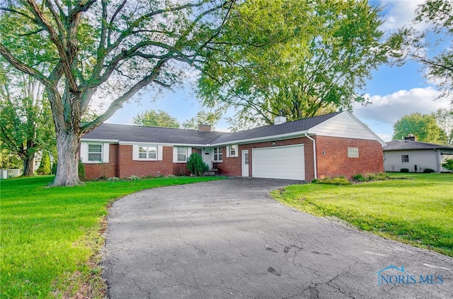 ranch-style home featuring a garage and a front lawn