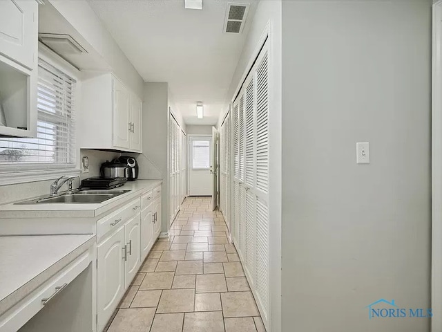 kitchen featuring white cabinetry, sink, and light tile patterned floors