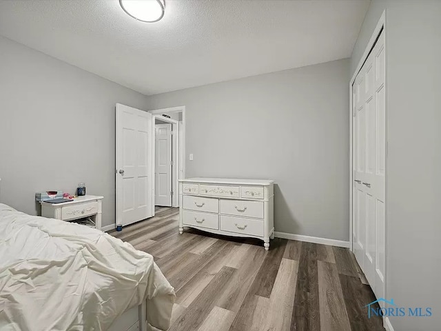 bedroom with light wood-type flooring, a textured ceiling, and a closet