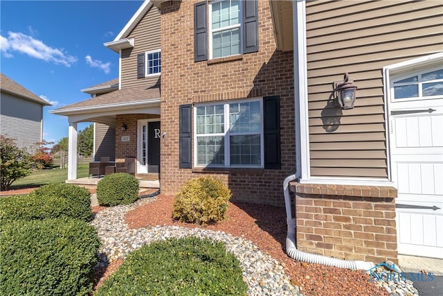 property entrance featuring covered porch and a garage