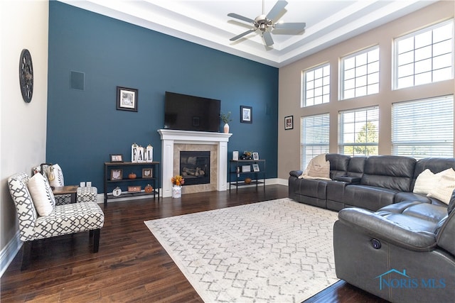 living room with a raised ceiling, ceiling fan, hardwood / wood-style flooring, and a tiled fireplace