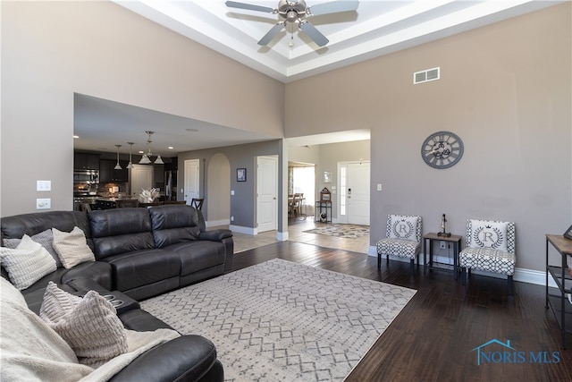 living room featuring a high ceiling, dark hardwood / wood-style flooring, and ceiling fan