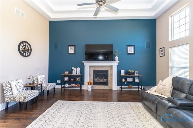 living room with ceiling fan, a fireplace, a raised ceiling, and hardwood / wood-style floors