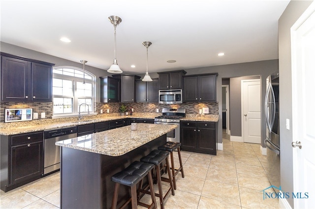 kitchen featuring a center island, a breakfast bar, sink, pendant lighting, and appliances with stainless steel finishes