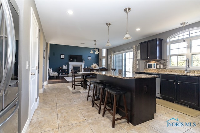 kitchen featuring a kitchen island, light stone countertops, stainless steel appliances, sink, and a breakfast bar area