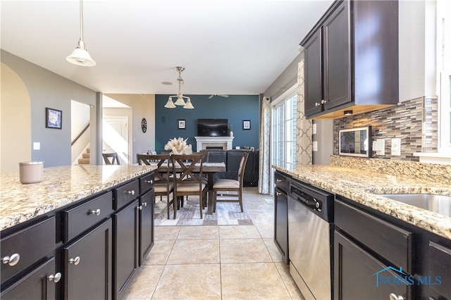 kitchen with pendant lighting, dark brown cabinets, backsplash, dishwasher, and light stone countertops