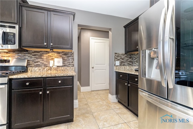 kitchen with tasteful backsplash, dark brown cabinets, light stone countertops, appliances with stainless steel finishes, and light tile patterned floors