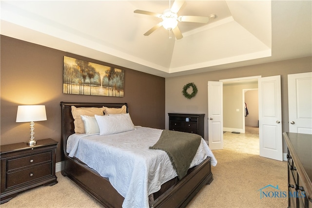 bedroom featuring ceiling fan, a raised ceiling, and light colored carpet