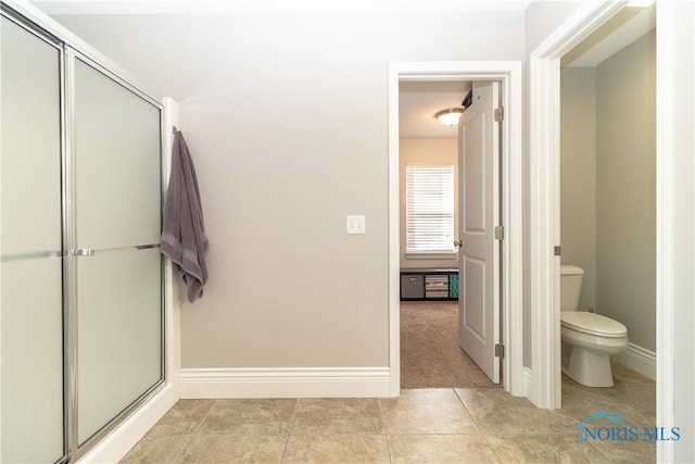 bathroom featuring tile patterned flooring, walk in shower, and toilet