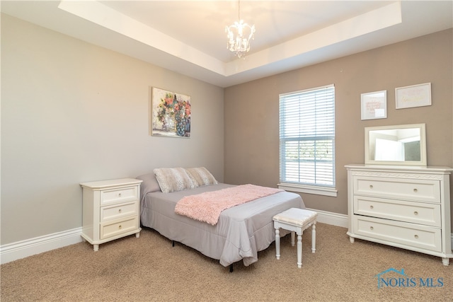 bedroom featuring light colored carpet, a tray ceiling, and a chandelier