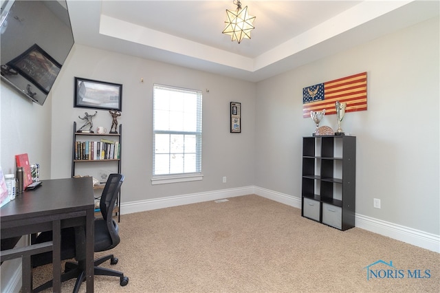 carpeted office space with a tray ceiling