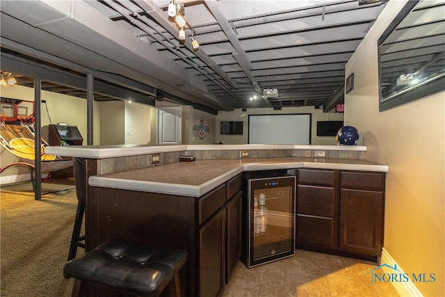 bar with light colored carpet, wine cooler, and dark brown cabinets