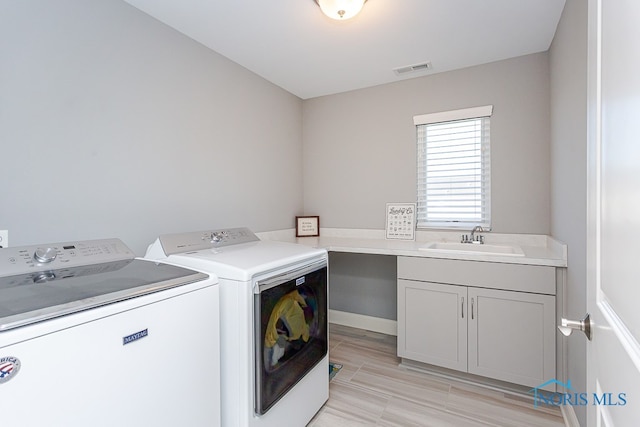 laundry room featuring cabinets, light hardwood / wood-style floors, sink, and washer and clothes dryer