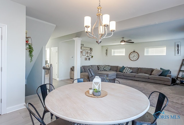 dining area with light hardwood / wood-style floors, ceiling fan with notable chandelier, and ornate columns