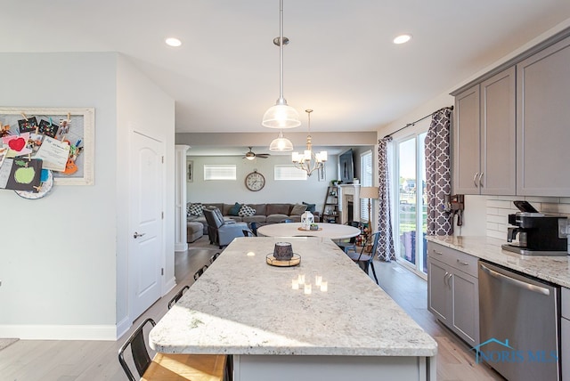 kitchen featuring light hardwood / wood-style floors, tasteful backsplash, light stone countertops, a center island, and dishwasher