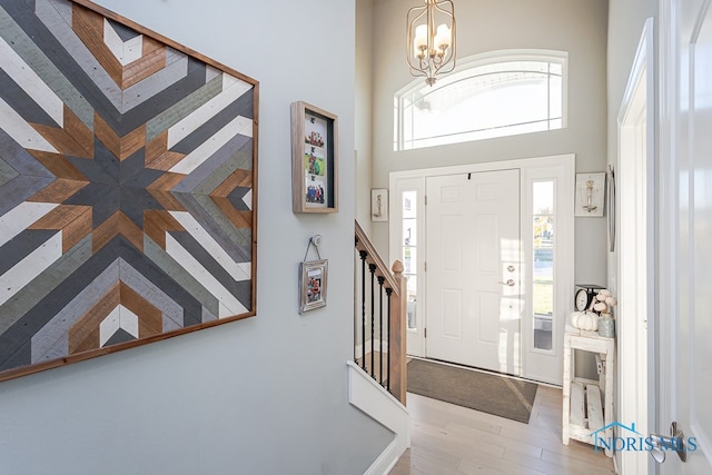 entryway with a towering ceiling, a wealth of natural light, light hardwood / wood-style floors, and a chandelier