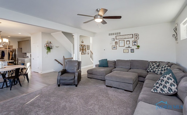 living room featuring ceiling fan with notable chandelier, hardwood / wood-style flooring, and decorative columns