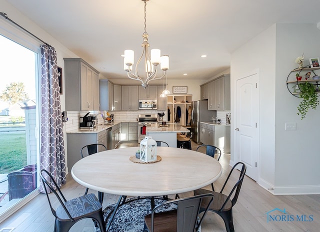 dining room with sink, an inviting chandelier, and light hardwood / wood-style flooring