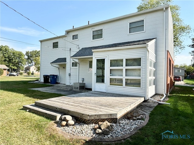 back of property with a deck, a yard, and central AC