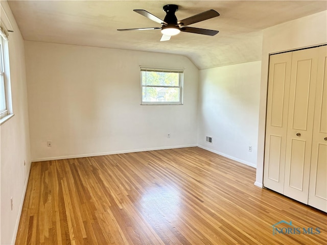 unfurnished bedroom featuring lofted ceiling, ceiling fan, light hardwood / wood-style flooring, and a closet