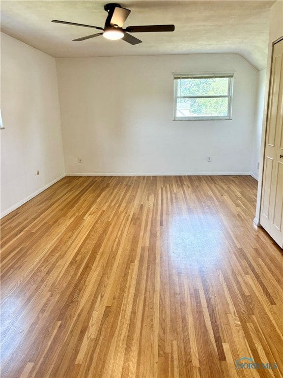 empty room featuring vaulted ceiling, light hardwood / wood-style floors, and ceiling fan