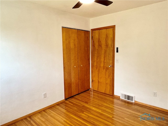 unfurnished bedroom featuring ceiling fan, hardwood / wood-style flooring, and a closet