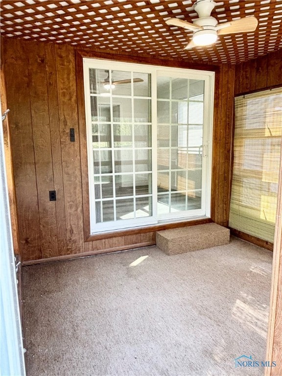 interior space with wooden walls and ceiling fan