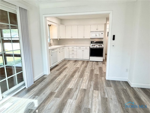 kitchen featuring white appliances, sink, light hardwood / wood-style flooring, and white cabinets