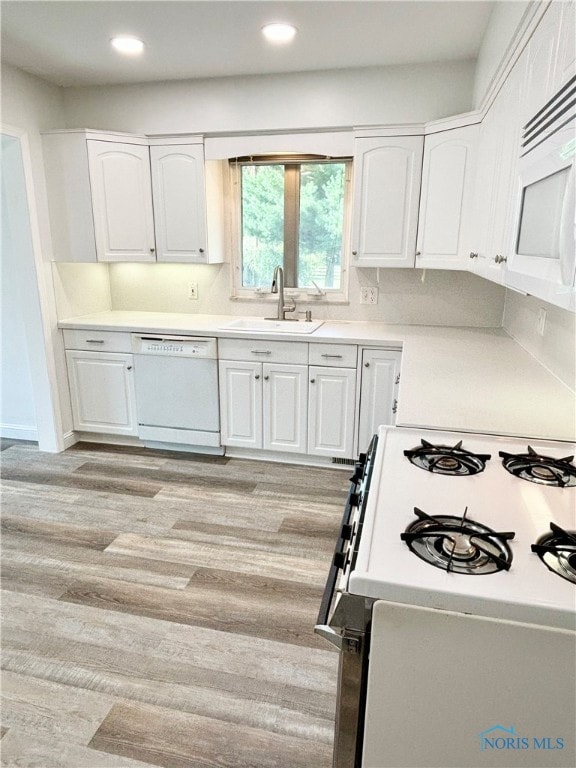 kitchen featuring white appliances, sink, light hardwood / wood-style flooring, and white cabinets