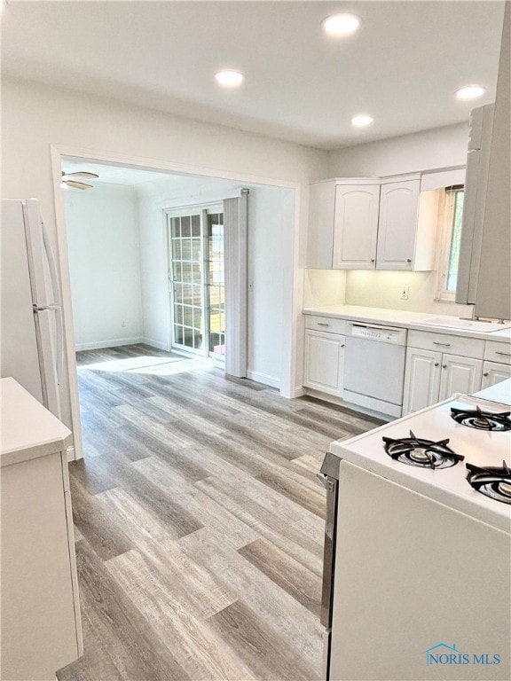 kitchen with white cabinets, light wood-type flooring, and white appliances