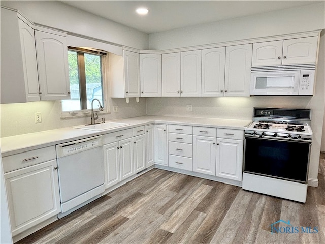 kitchen with light hardwood / wood-style floors, white appliances, sink, and white cabinets