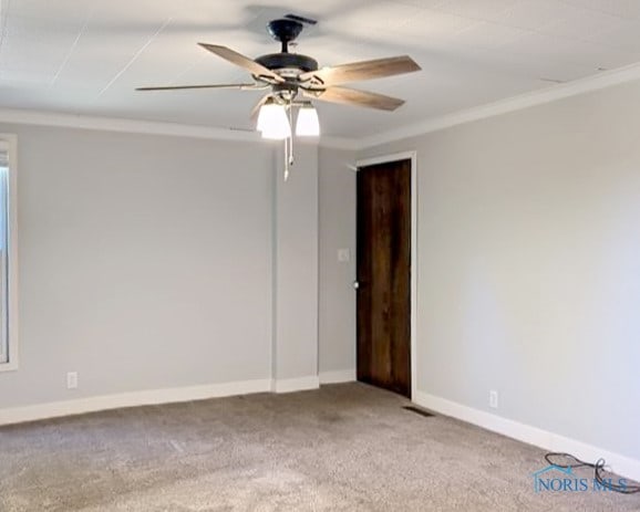 carpeted spare room featuring ceiling fan and crown molding